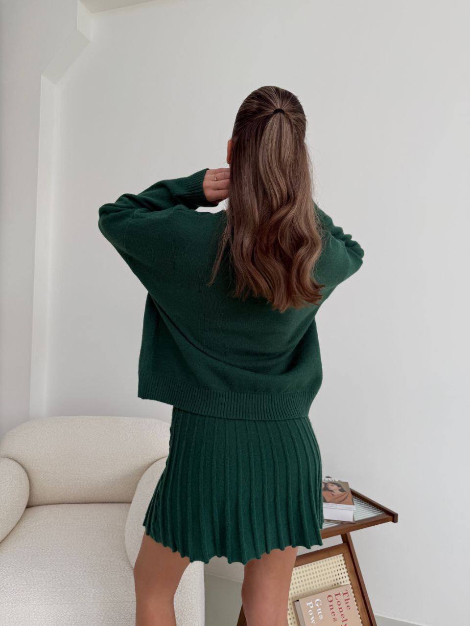Kostým, který se skládá ze svetru a plisované sukně