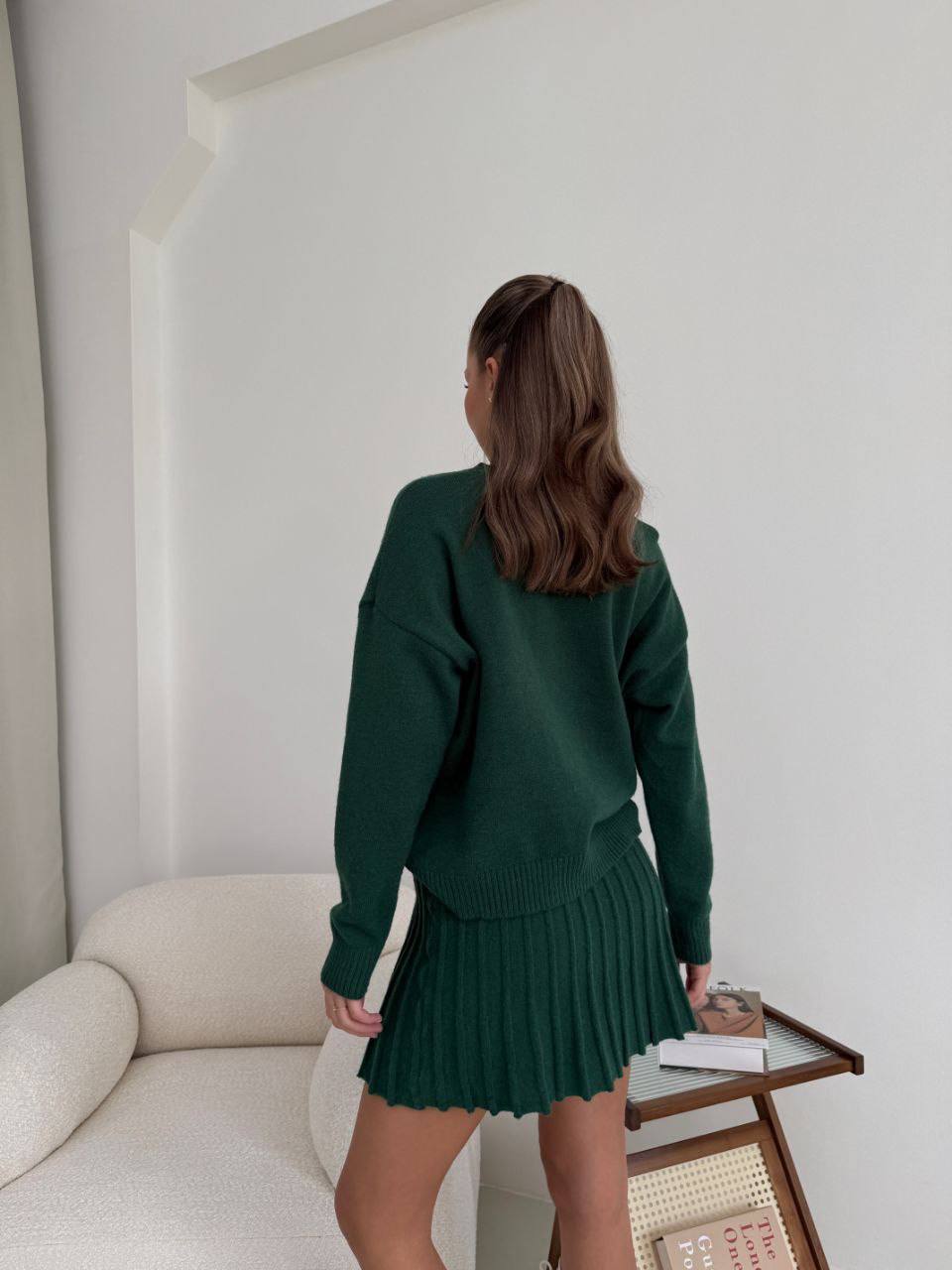 Kostým, který se skládá ze svetru a plisované sukně