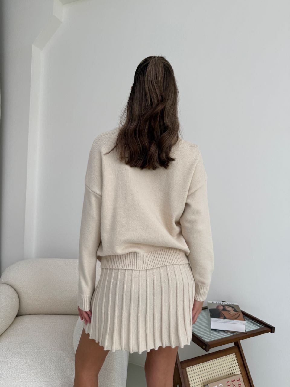 Kostým, který se skládá ze svetru a plisované sukně