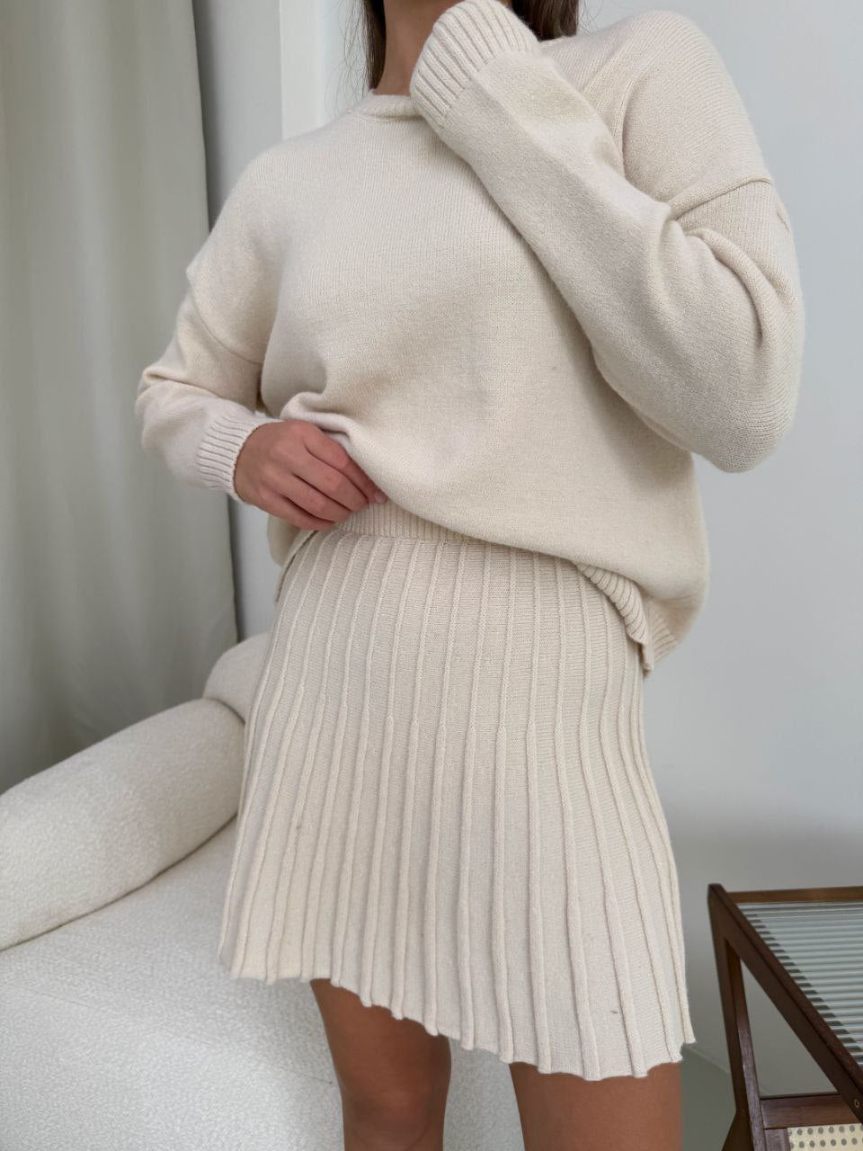 Kostým, který se skládá ze svetru a plisované sukně